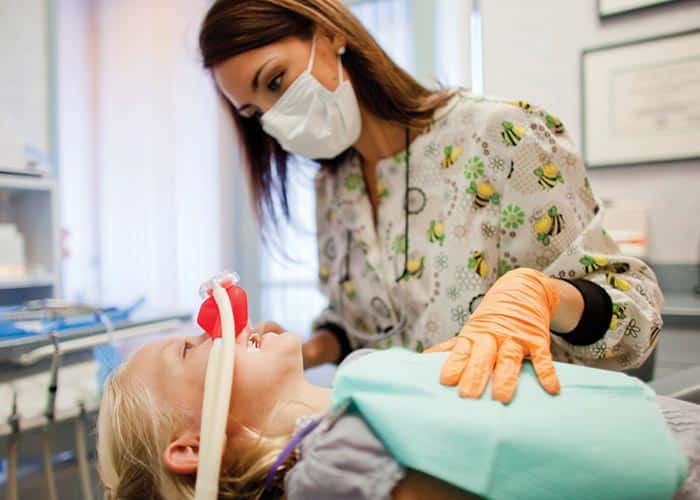 Dental assistant checking on child patient